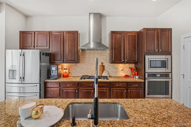 a kitchen with granite countertop a refrigerator and a stove top oven