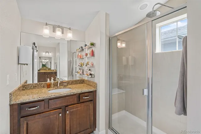 a bathroom with a granite countertop sink a toilet a mirror and shower