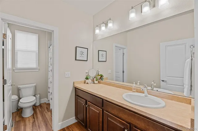 a bathroom with a granite countertop toilet a sink and a mirror