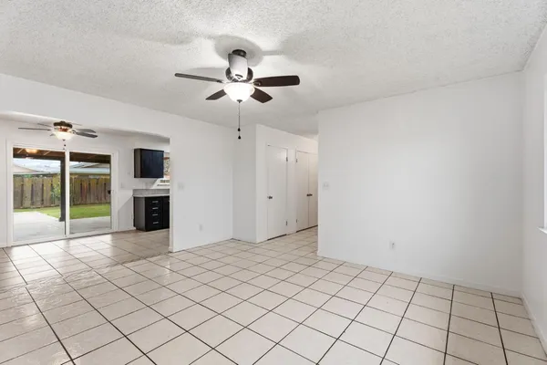a view of an empty room with a fireplace and a chandelier fan