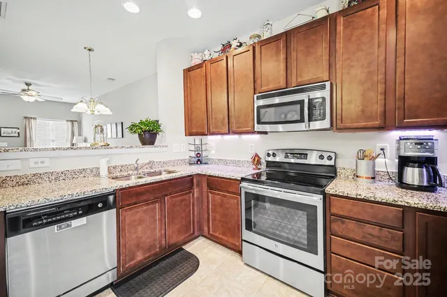 a kitchen with granite countertop a sink stove and microwave
