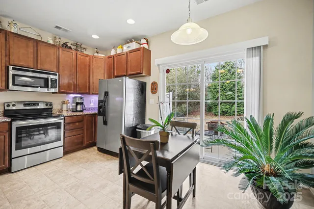 a kitchen with stainless steel appliances a refrigerator a stove a sink cabinets and a dining table