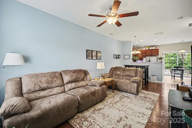 a living room with furniture kitchen view and a chandelier