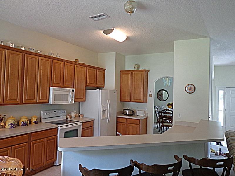 54399 Church Road Callahan, FL 32011 - Photo 26 of 49 a kitchen with granite countertop a stove a refrigerator and wooden table