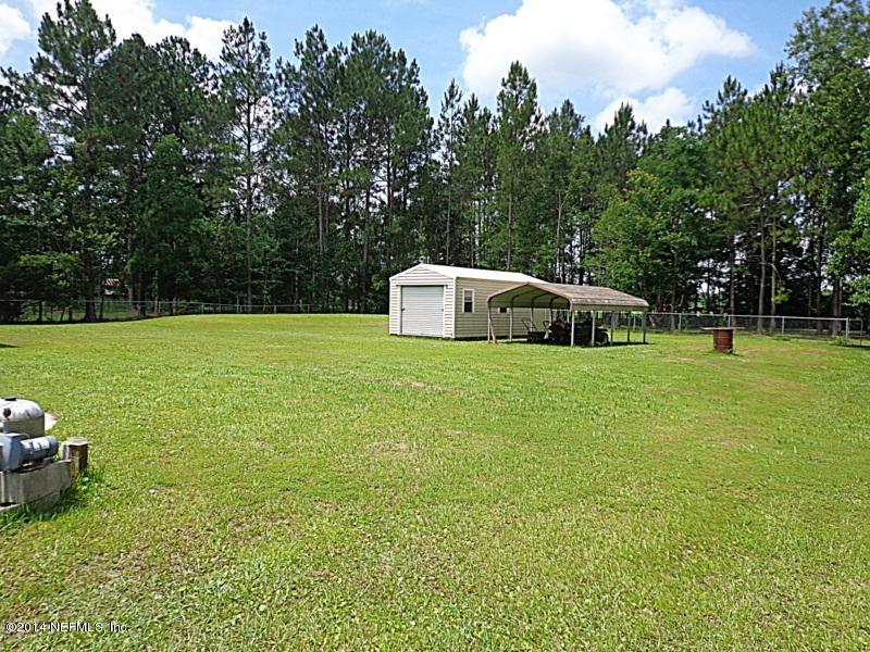 54399 Church Road Callahan, FL 32011 - Photo 10 of 49 a white house with a big yard and large trees