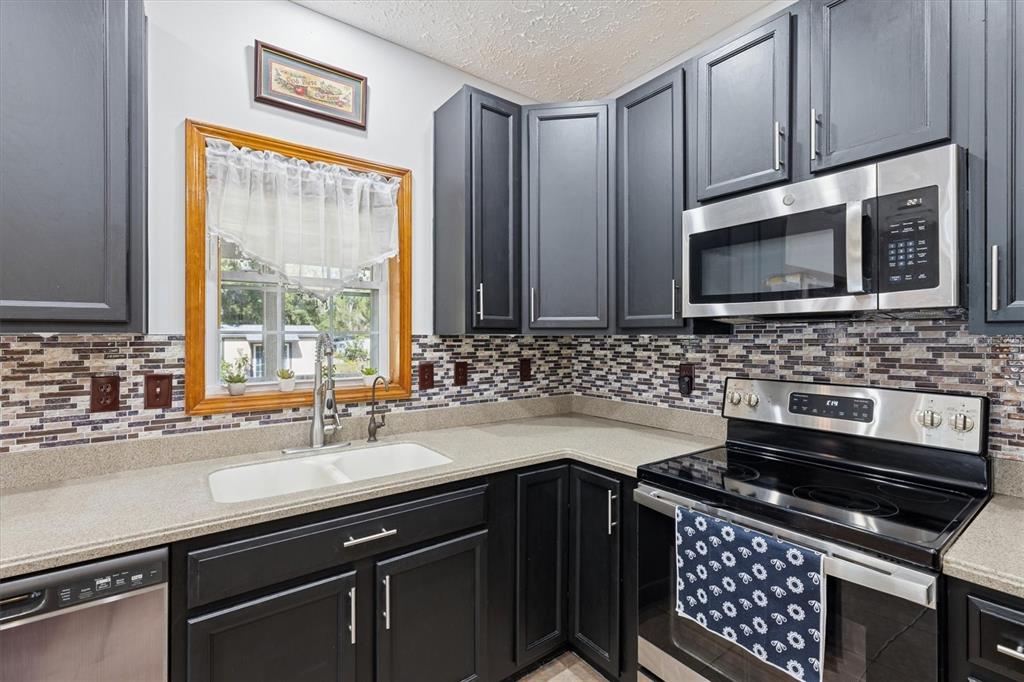 16607 Bearle Road Orlando, FL 32828 - Photo 31 of 57 a kitchen with stainless steel appliances a sink stove and microwave