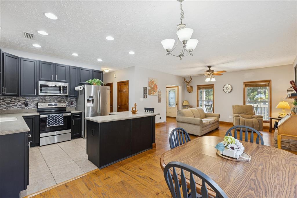 16607 Bearle Road Orlando, FL 32828 - Photo 34 of 57 a kitchen with stainless steel appliances kitchen island granite countertop a refrigerator a stove a sink dishwasher a dining table and chairs with wooden floor