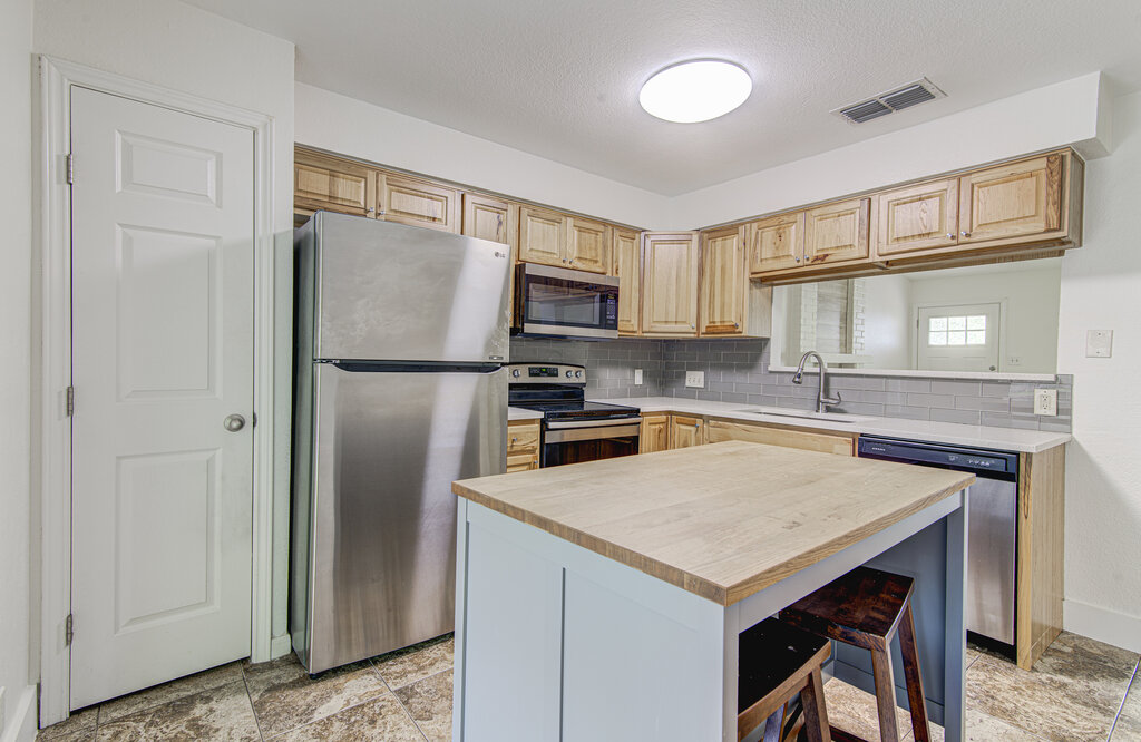 6713 West Gate Boulevard, Unit A Austin, TX 78745 - Photo 8 of 21 a kitchen with a refrigerator a stove a sink and a microwave