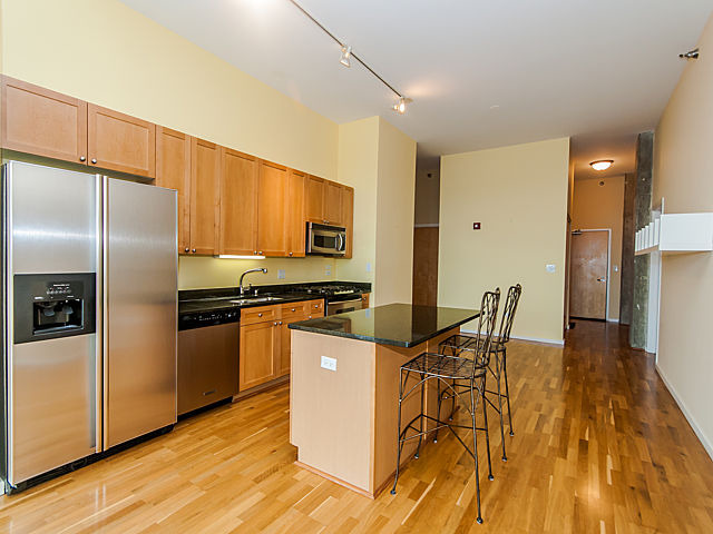 321 South Sangamon Street, Unit 901 Chicago, IL 60607 - Photo 5 of 18 a kitchen with stainless steel appliances a refrigerator a stove a sink a dining table and chairs with wooden floor