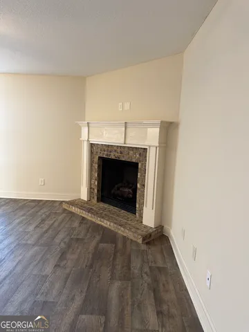 a view of an empty room with wooden floor fireplace and a window