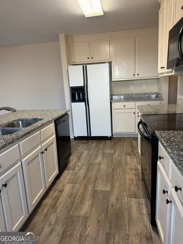 a kitchen with granite countertop white cabinets and white appliances