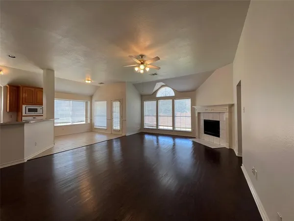 an empty room with wooden floor fireplace and windows