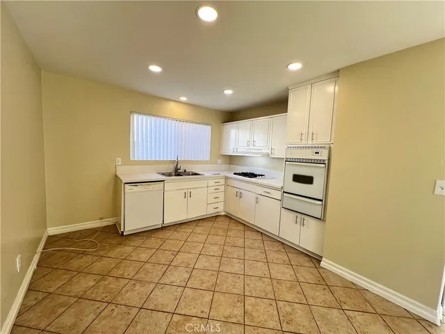 a kitchen with white cabinets a sink stove and refrigerator