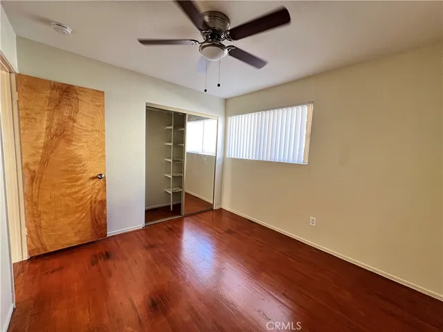 an empty room with wooden floor chandelier fan and windows