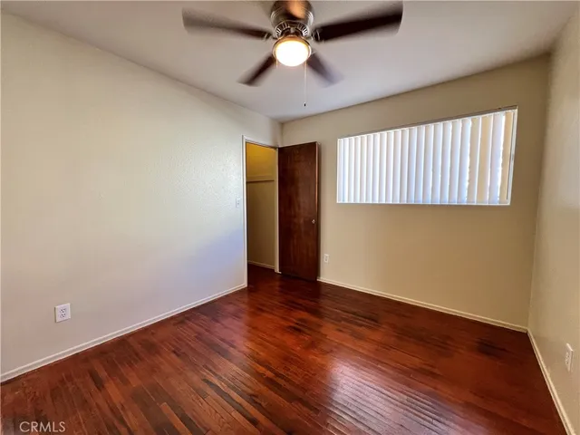 an empty room with wooden floor chandelier fan and windows