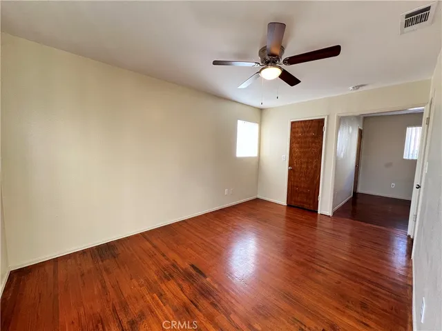 an empty room with wooden floor ceiling fan and window
