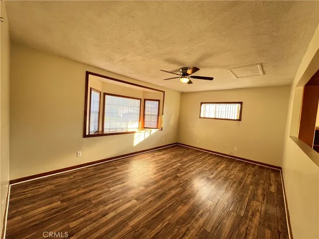 a view of an empty room with a window and wooden floor