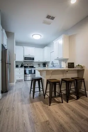 a kitchen with stainless steel appliances a table chairs refrigerator sink and cabinets