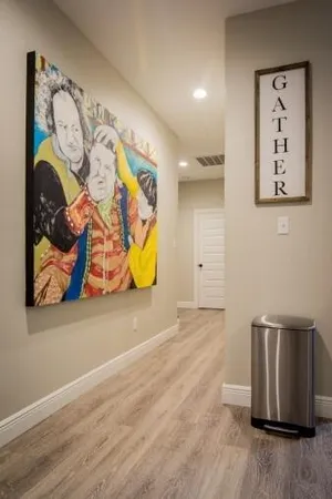 a view of a hallway with wooden floor and paintings on the wall