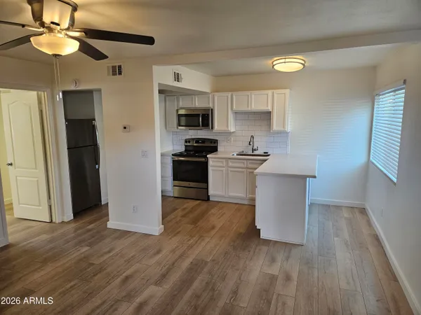 a kitchen with stainless steel appliances a sink a stove a refrigerator cabinets and wooden floor