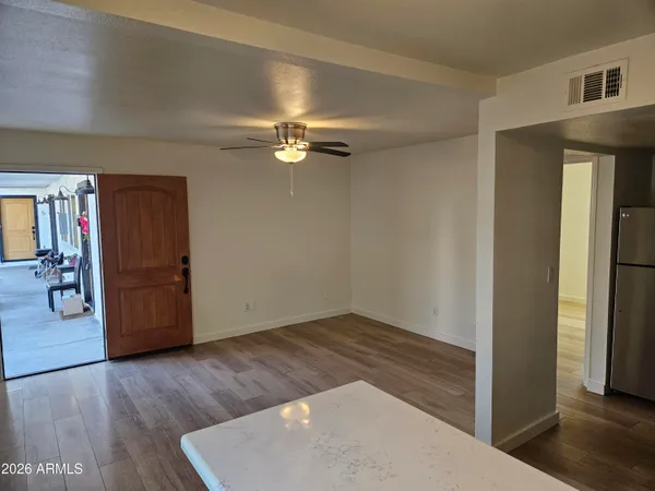 an empty room with wooden floor chandelier fan and windows