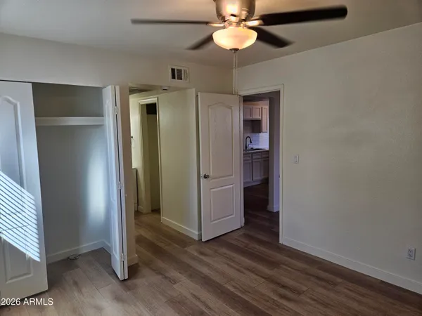 an empty room with wooden floor a ceiling fan and closet area