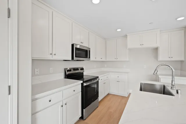 a kitchen with white cabinets stainless steel appliances and sink