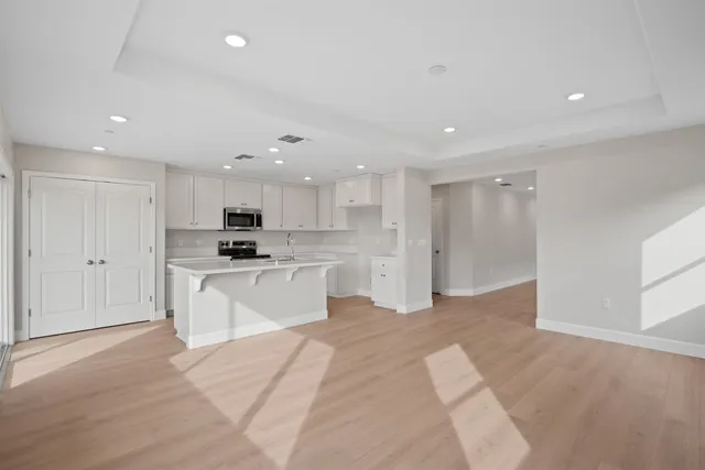 a large white kitchen with kitchen island a sink a center island stainless steel appliances and a cabinets