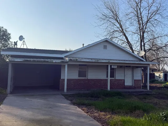 a view of a house with a yard plants and large tree
