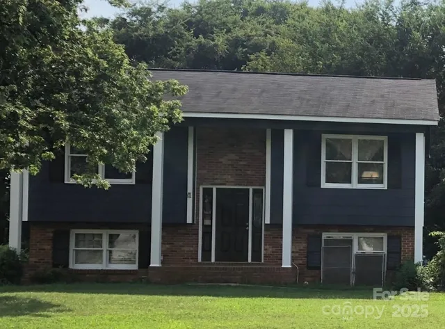 a view of a house with yard and large tree