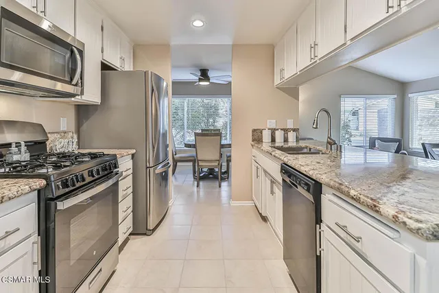 a kitchen with stainless steel appliances granite countertop a stove top oven a sink dishwasher a refrigerator and a microwave