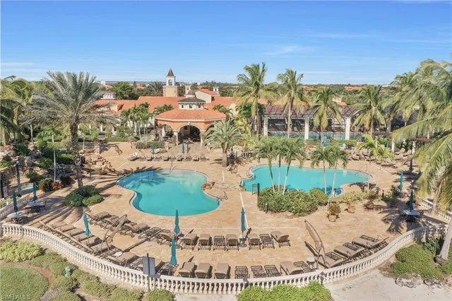 a view of a swimming pool with a table and chairs in front of house