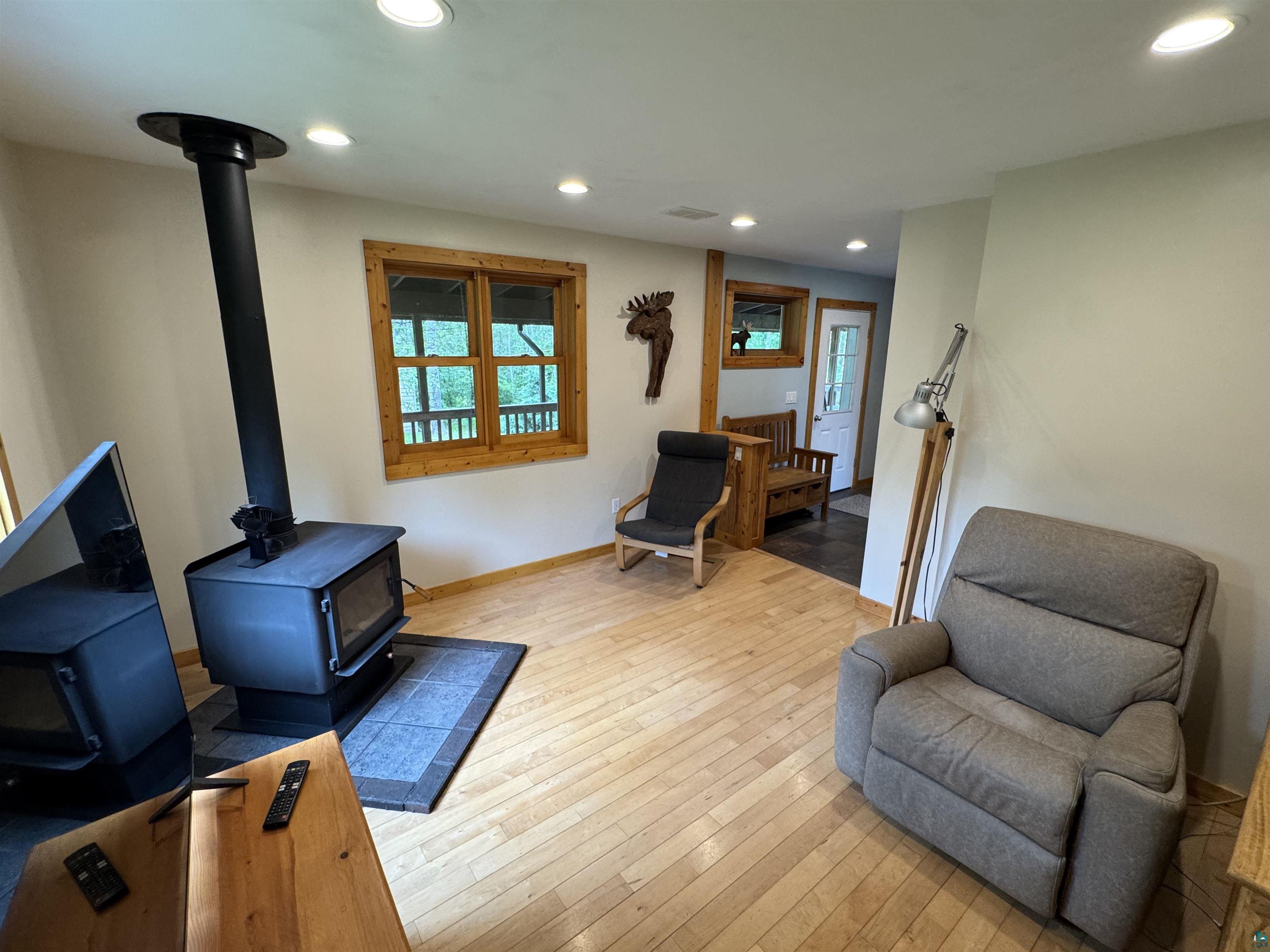 1745 Becks Road Maple, WI 54854 - Photo 7 of 46 Living space featuring wood-finish flooring, recessed lighting, and a prominent wood-burning stove on a dark tile hearth
