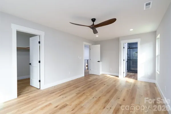 a view of empty room with wooden floor and fan