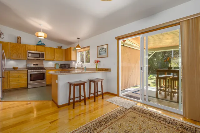 a kitchen with stainless steel appliances granite countertop a stove top oven a sink a dining table and chairs