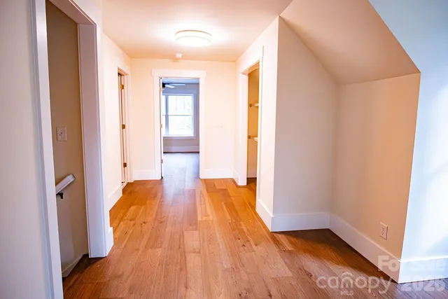 an empty room with wooden floor fan and windows