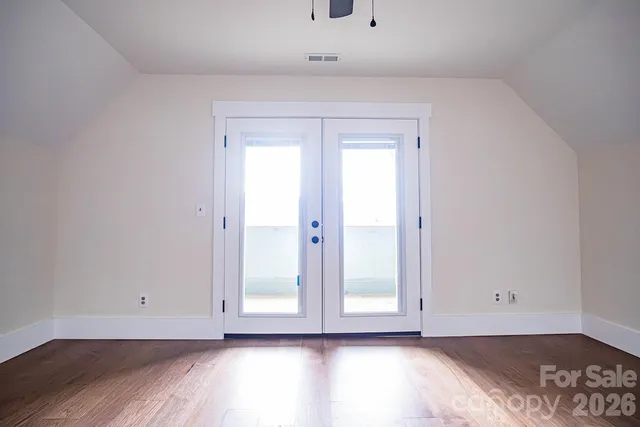 an empty room with wooden floor cabinet and windows