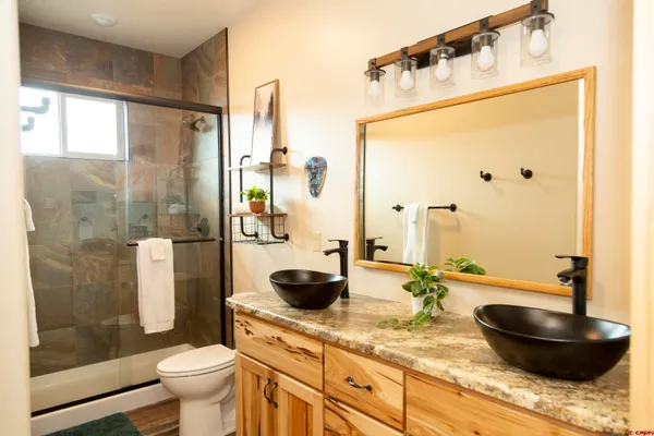 a bathroom with a granite countertop sink a toilet and shower