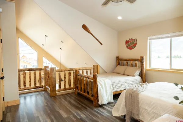 a bedroom with a bed and a large window with wooden floor