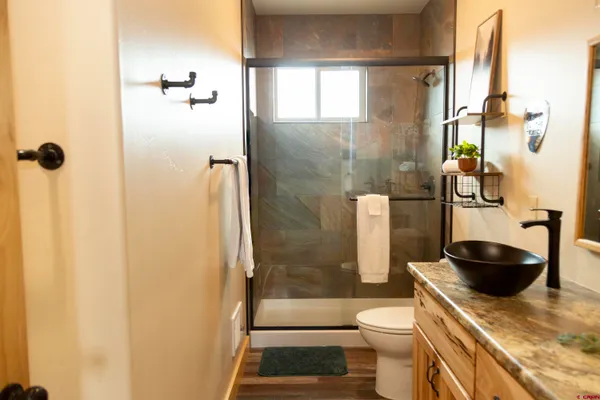 a bathroom with a granite countertop toilet a sink and shower