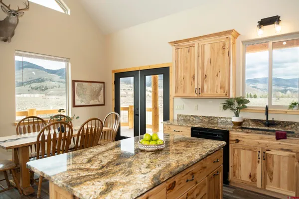 a kitchen with stainless steel appliances granite countertop a stove a sink a dining table and chairs with wooden floor