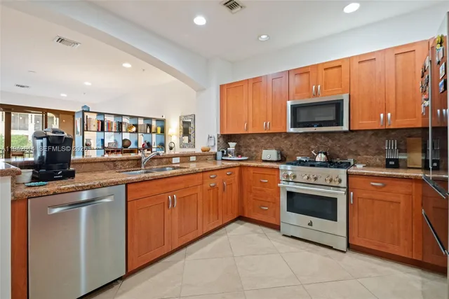 a kitchen with stainless steel appliances granite countertop a stove top oven a sink dishwasher and a microwave oven with large cabinets