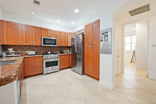 a kitchen with stainless steel appliances granite countertop a refrigerator and a stove top oven