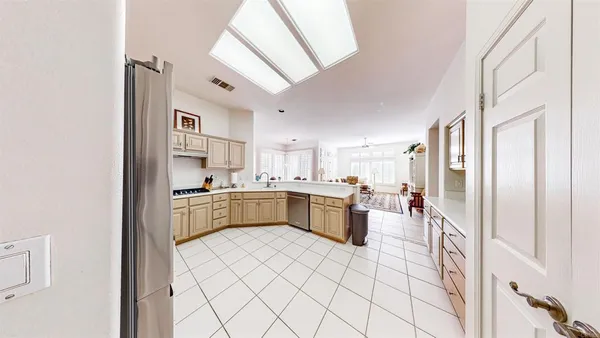 a large white kitchen with a sink and dishwasher a refrigerator with white cabinets