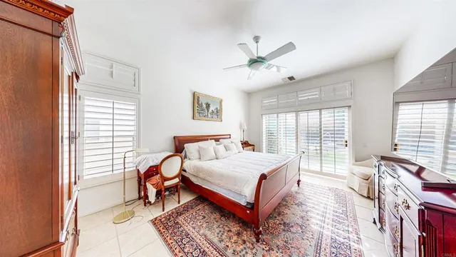 a bedroom with a bed lamp on desk and a window