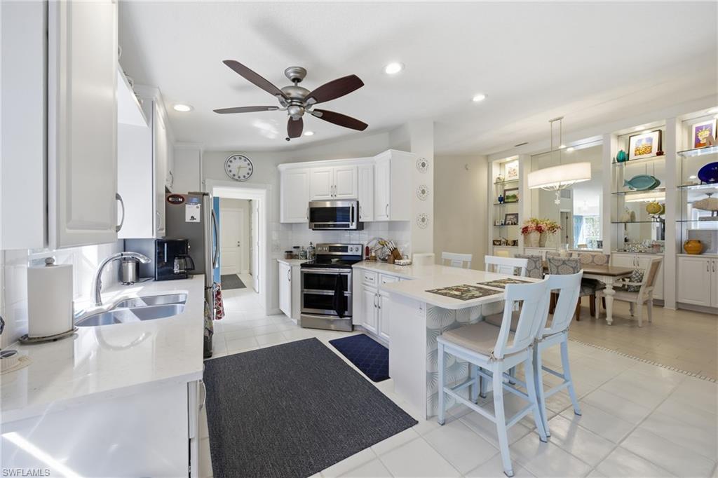 3614 El Segundo Court Naples, FL 34109 - Photo 11 of 49 a kitchen with stainless steel appliances kitchen island granite countertop a sink and cabinets