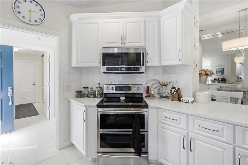 3614 El Segundo Court Naples, FL 34109 - Photo 14 of 49 a kitchen with white cabinets and a stove with a sink