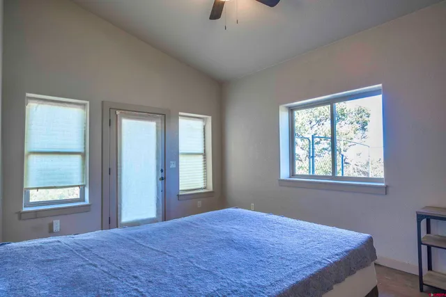 a bedroom with a bed and window with wooden floor