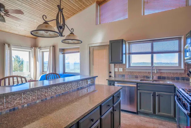 a dining hall with stainless steel appliances granite countertop a sink a stove and a wooden floors