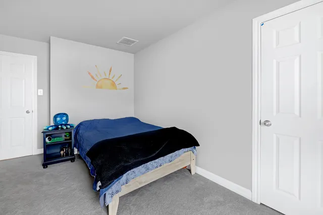 a bedroom with a bed and painting on the wall